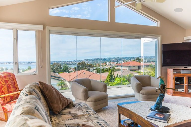 Looking from living room into patio with enclosed frameless sliding glass doors with door swung open.