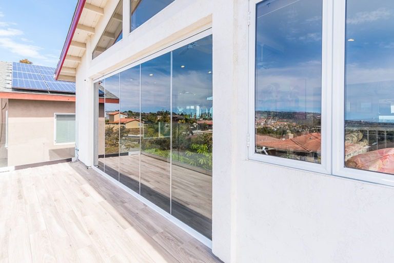 From wood floor patio looking at enclosed frameless sliding glass doors.