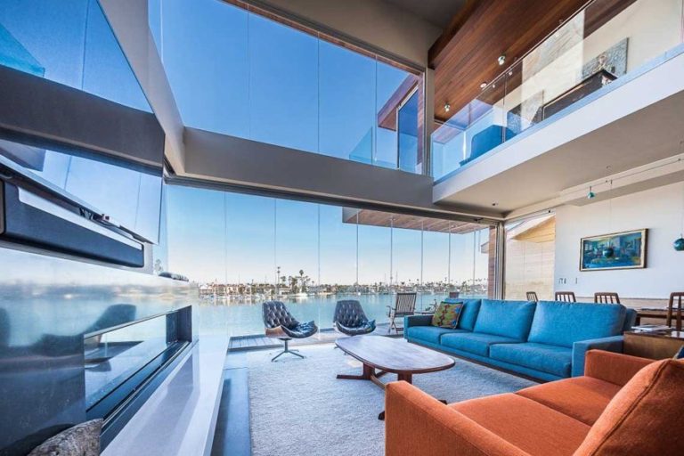 Living room with enclosed frameless sliding glass doors and view of bay.