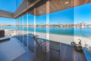 Staggered frameless sliding glass doors with view of patio and bay.