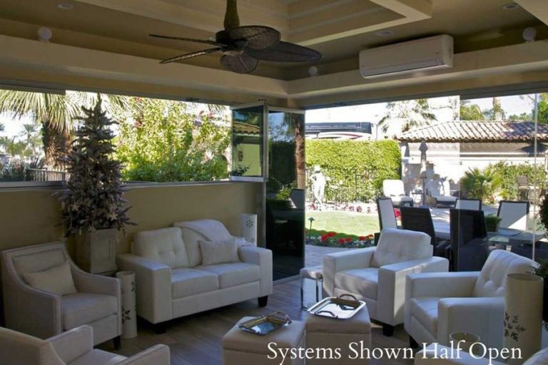 Indoor patio with white sofas and half open glass panels connecting to the yard.