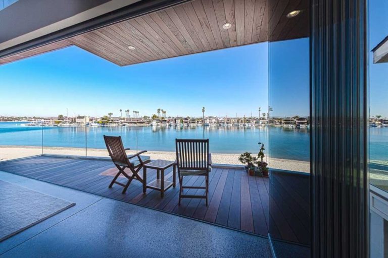 Stacked frameless sliding glass doors with view of patio and bay.