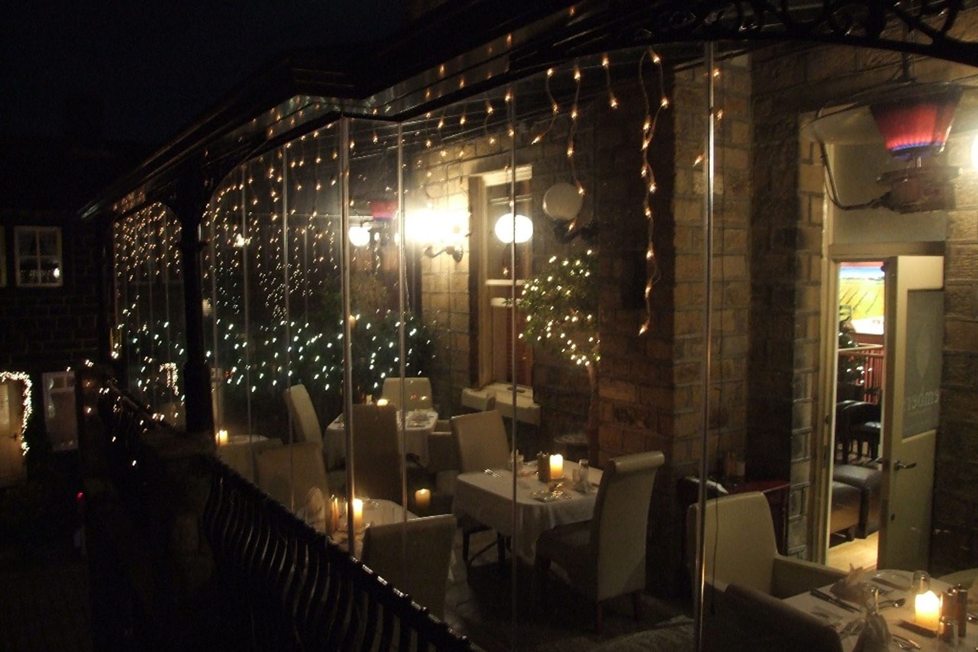 Enclosed restaurant patio with frameless sliding glass doors.