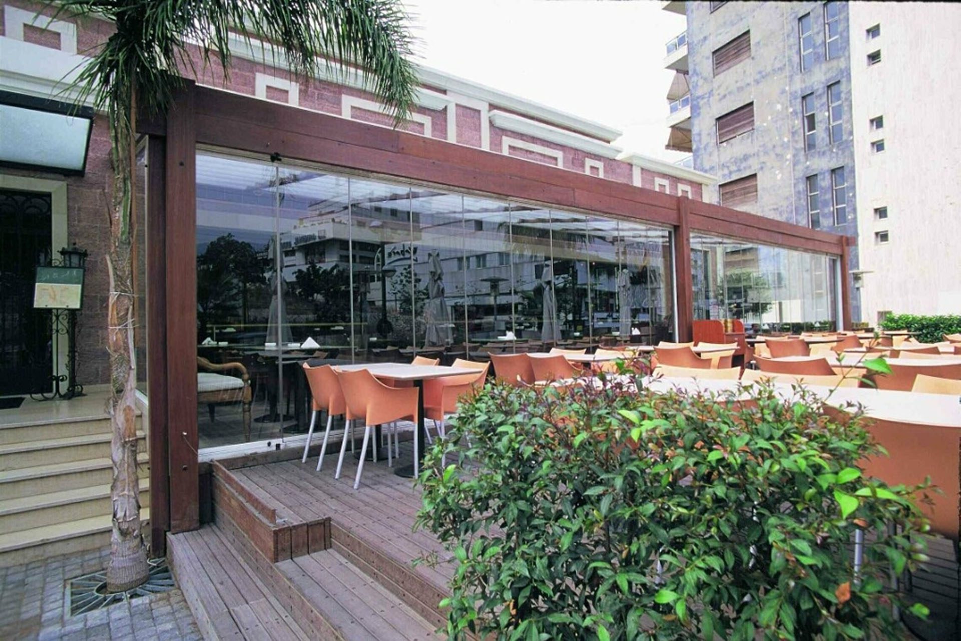 Patio tables next to enclosed frameless sliding glass doors in restaurant.