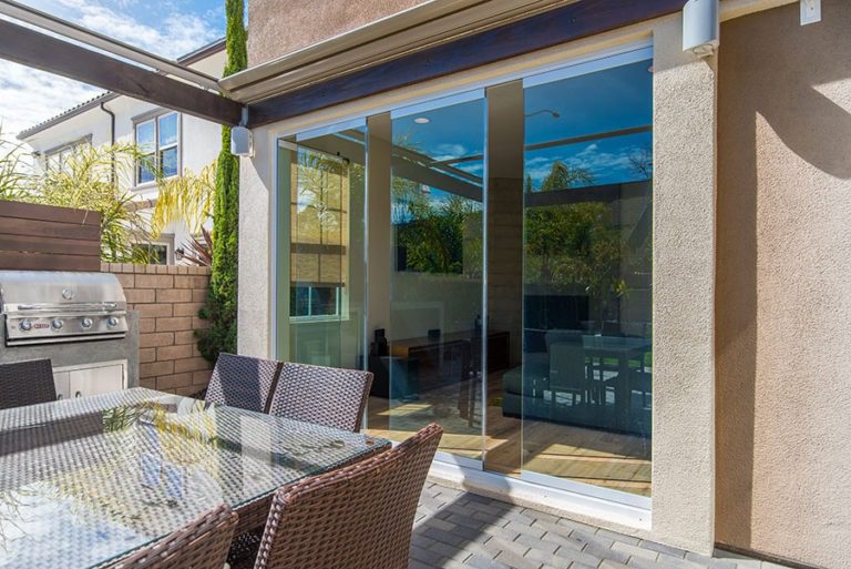 Looking from patio into living room with staggered frameless sliding glass doors.