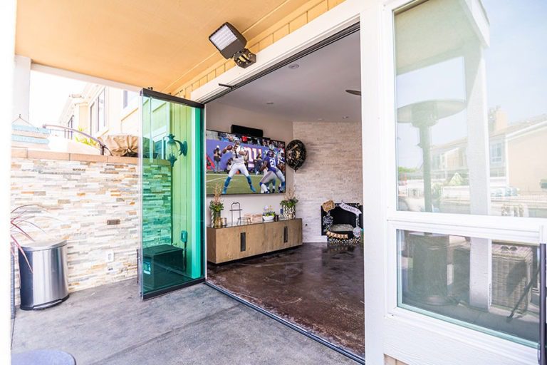 Outdoor area with stacked frameless sliding glass doors looking into living room.