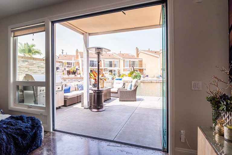 Living space with fully stacked sliding glass doors connecting to an outdoor area with table and chairs.