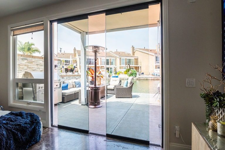 Living space with partially open sliding glass doors connecting to an outdoor area with table and chairs.