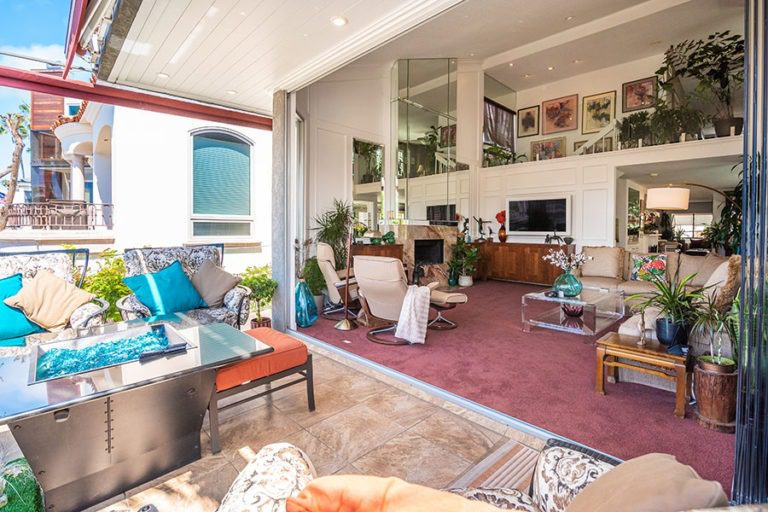 Open concept living room with fully stacked frameless glass doors connecting to the patio.