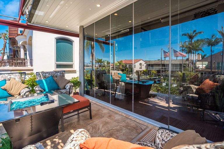 Patio area with closed frameless sliding glass doors reflecting the outdoors.