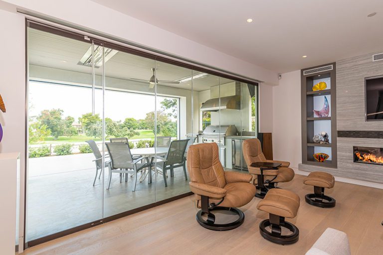 Closed frameless sliding glass doors separating a living space from patio and back yard.