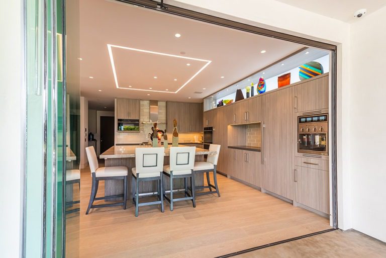 Fully stacked sliding glass doors showing a spacious kitchen and dining room.