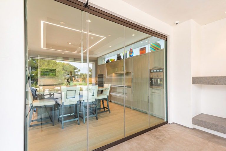 Closed frameless sliding glass doors showing kitchen area from patio.