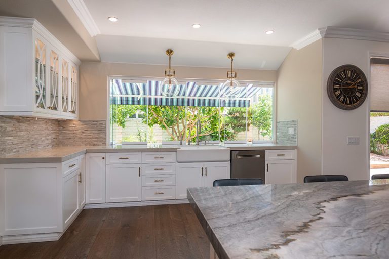 Frameless glass sliding doors staggered on marbled kitchen counter top next to kitchen island.