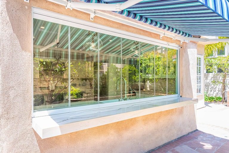 Looking at enclosed frameless glass windows on top of marble kitchen countertop.