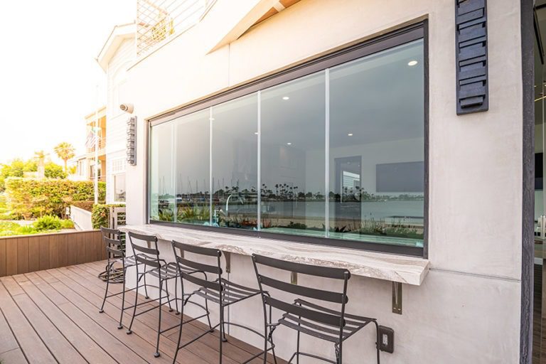 The sliding glass window is enclosed on top of the marbled kitchen counter while looking in from the wood patio floor.