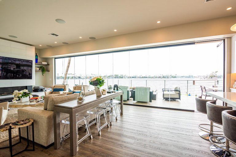 Open concept living room and kitchen with wood flooring and enclosed frameless glass sliding doors.