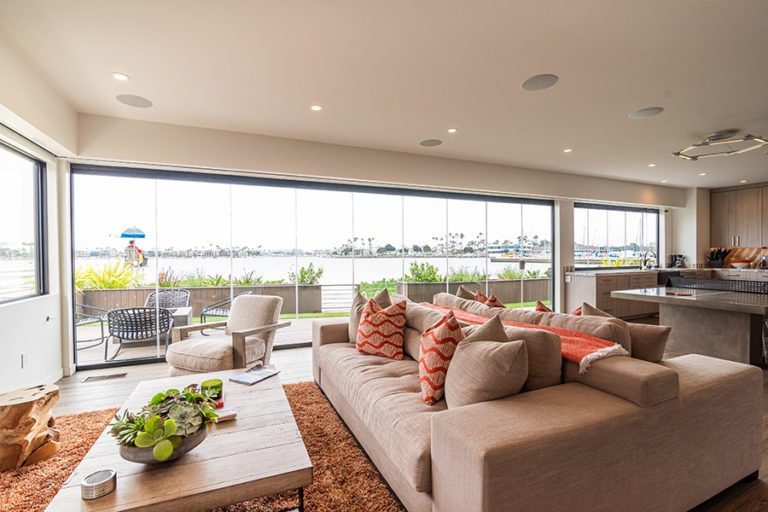 Beautifully designed open concept living room and kitchen with enclosed frameless glass doors and windows allowing for views of the boat docks.