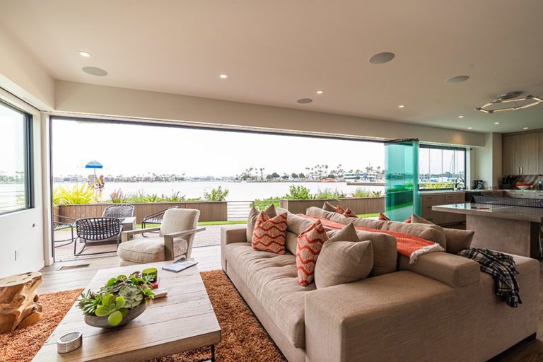 Views of the boat dock from the open concept living room and kitchen with frameless glass doors stacked to right side of room.