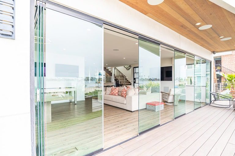 Frameless glass doors staggered in doorway between open concept living room and patio.